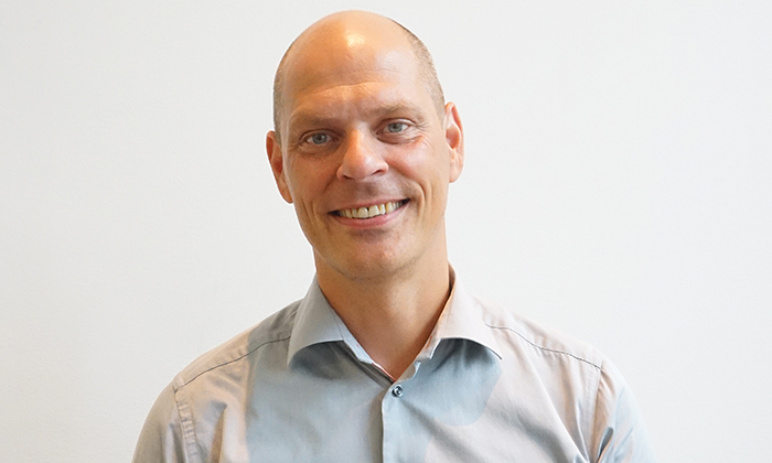 Man i ljusblå skjorta framför en vit bakgrund.