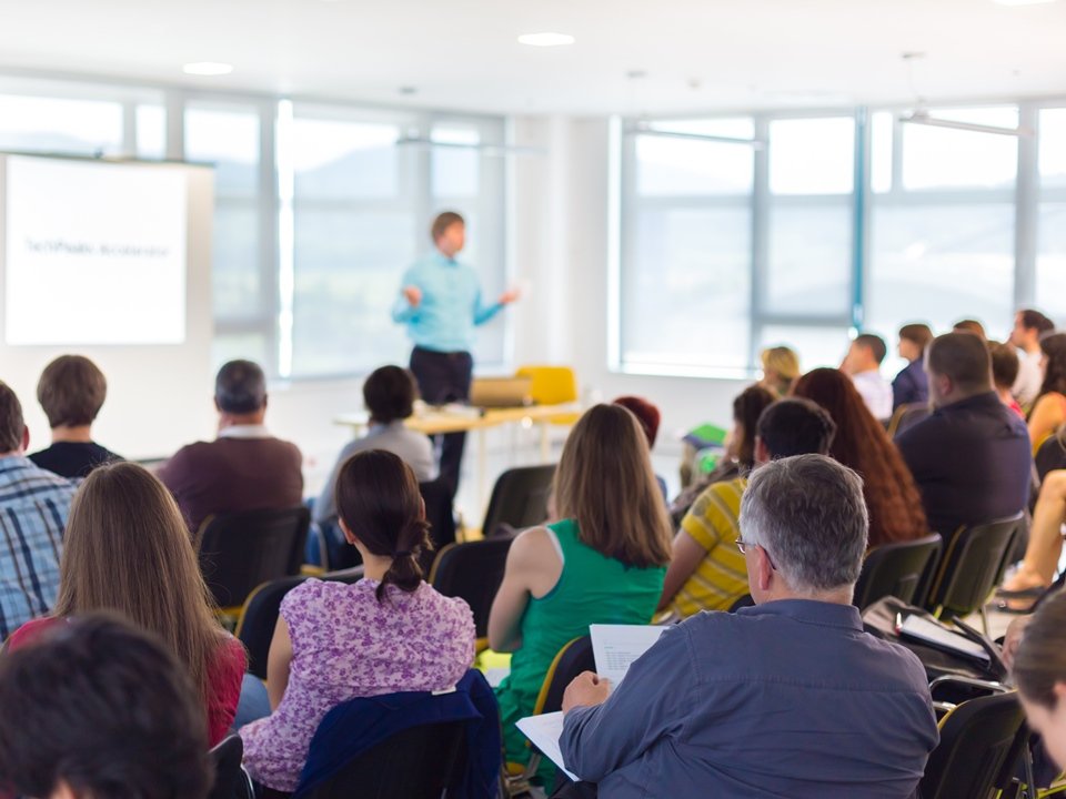 Audience attentively listening to a presentation in a bright, modern conference room