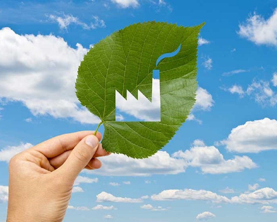 leaf with a cut out depiction of a factory with a smokey chimney, being help up to the sky