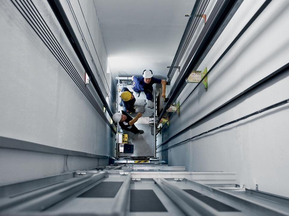 three employees doing an inspection of a lift 