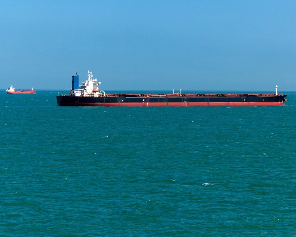 Cargo ship sailing in calm blue ocean under clear sky