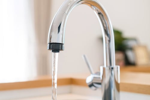 Kromad kökskran med rinnande vatten i en modern köksmiljö.