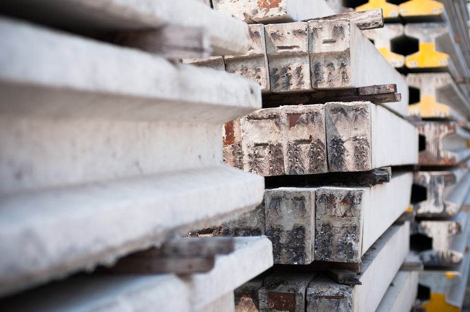 Stapel van betonnen panelen en bouwmaterialen in een industriële omgeving.