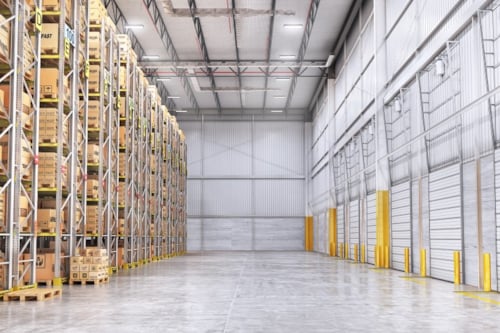 Opslagruimte met stellingen gevuld met dozen aan de linkerzijde en een lege vloer met gesloten roldeuren aan de rechterzijde.