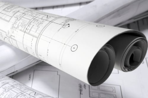 Opgerolde bouwtekeningen en technische plannen op een tafel.