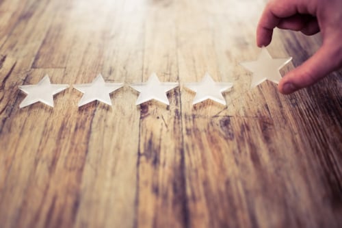 En gengrebild som visar en hand som placerar en stjärna bland fyra andra stjärnor på ett träbord som exemplifierar metodisk process för att nå framgång.