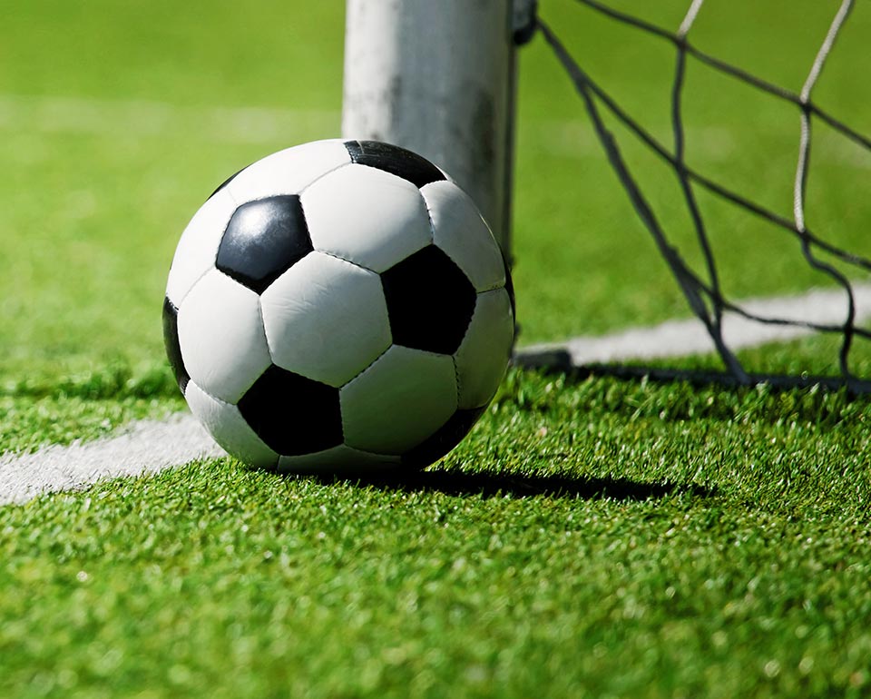 Fotboll på gräsplan nära mål med nät.