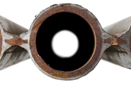 Tvärsnitt av ett rör med synlig rost och ett cirkulärt hål i mitten.