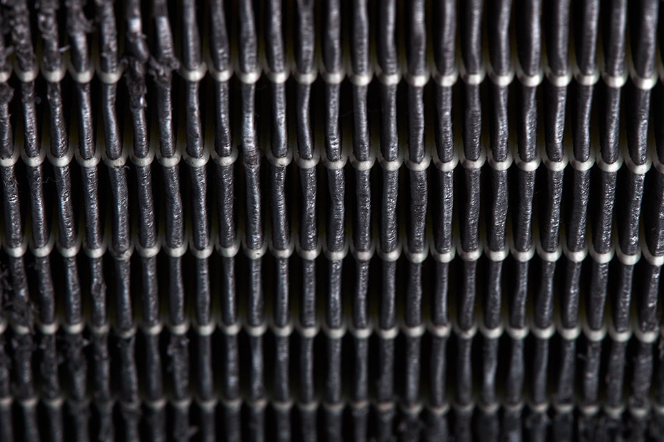 Close-up of industrial woven metallic mesh with vertical and horizontal black threads forming a grid pattern