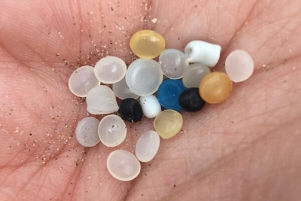 Gránulos de plástico de diferentes colores sostenidos en una mano.