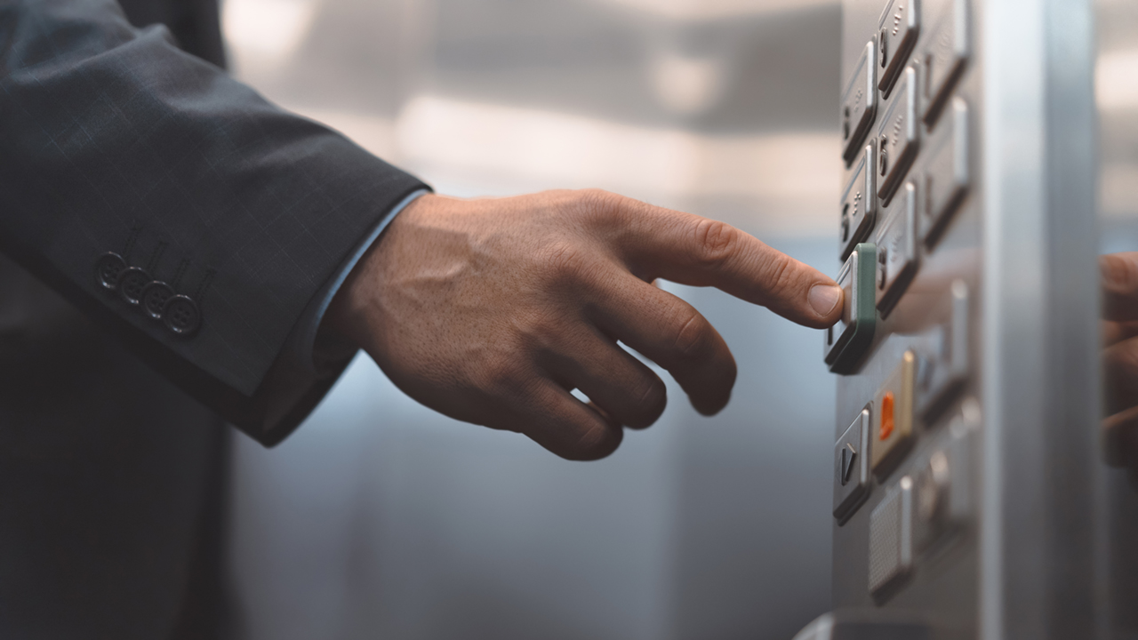 En person trycker på hissknappar. 