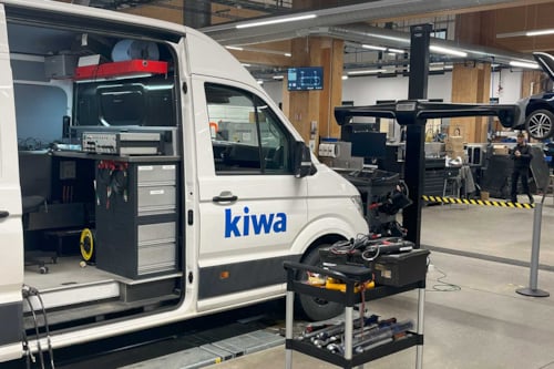 Skåpbil, endast dess vänstersida med ena framlyktan visas, som används för våra mobila kalibreringstjänster, kör på en väg.