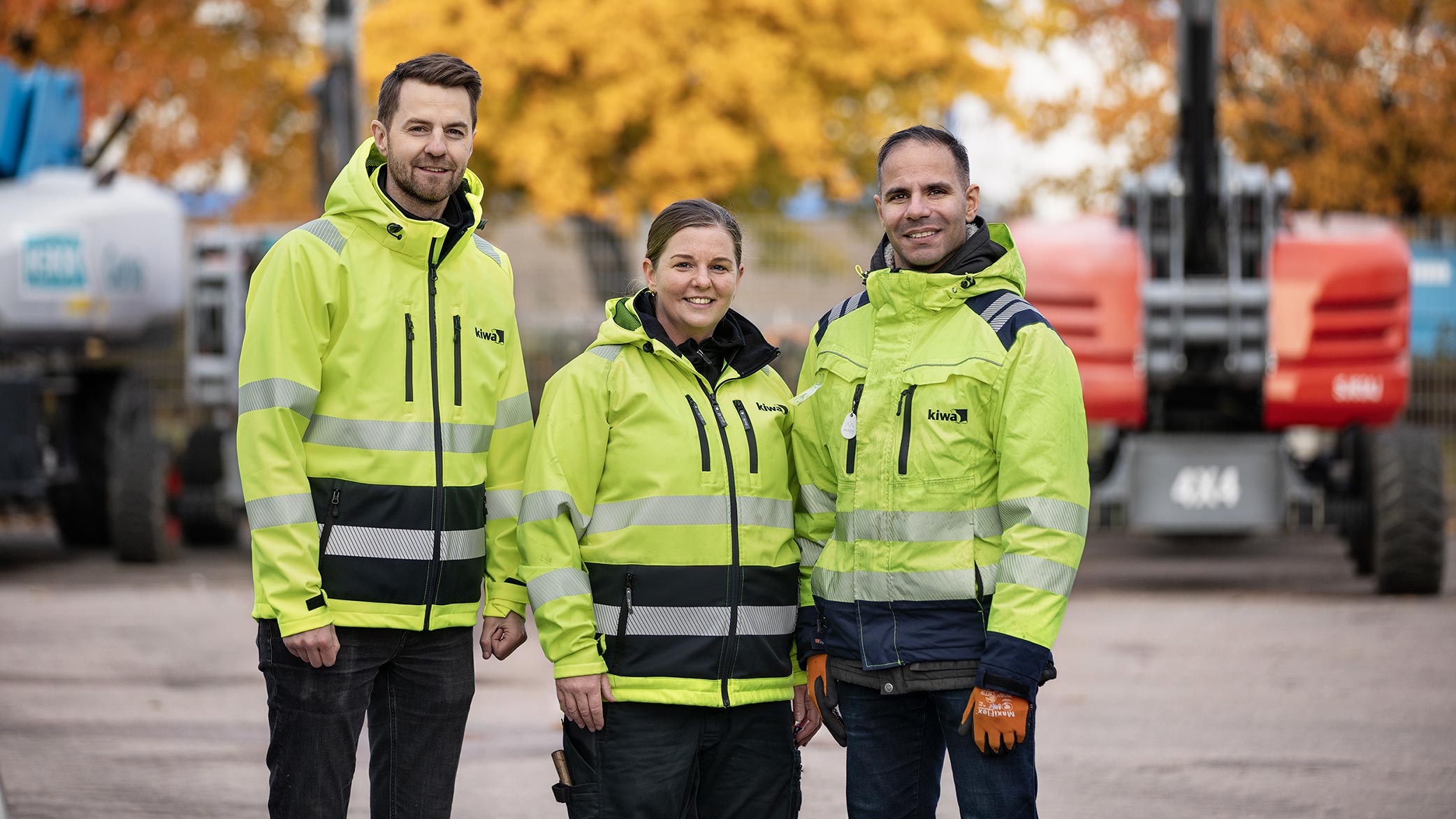 Tre stycken besiktningsingenjörer från Kiwa står uppställda framför kranbilar. 