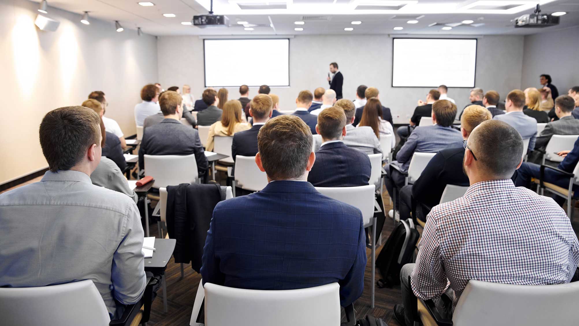 Företagsseminarium med åhörare som sitter i ett konferensrum och lyssnar på en föreläsare.