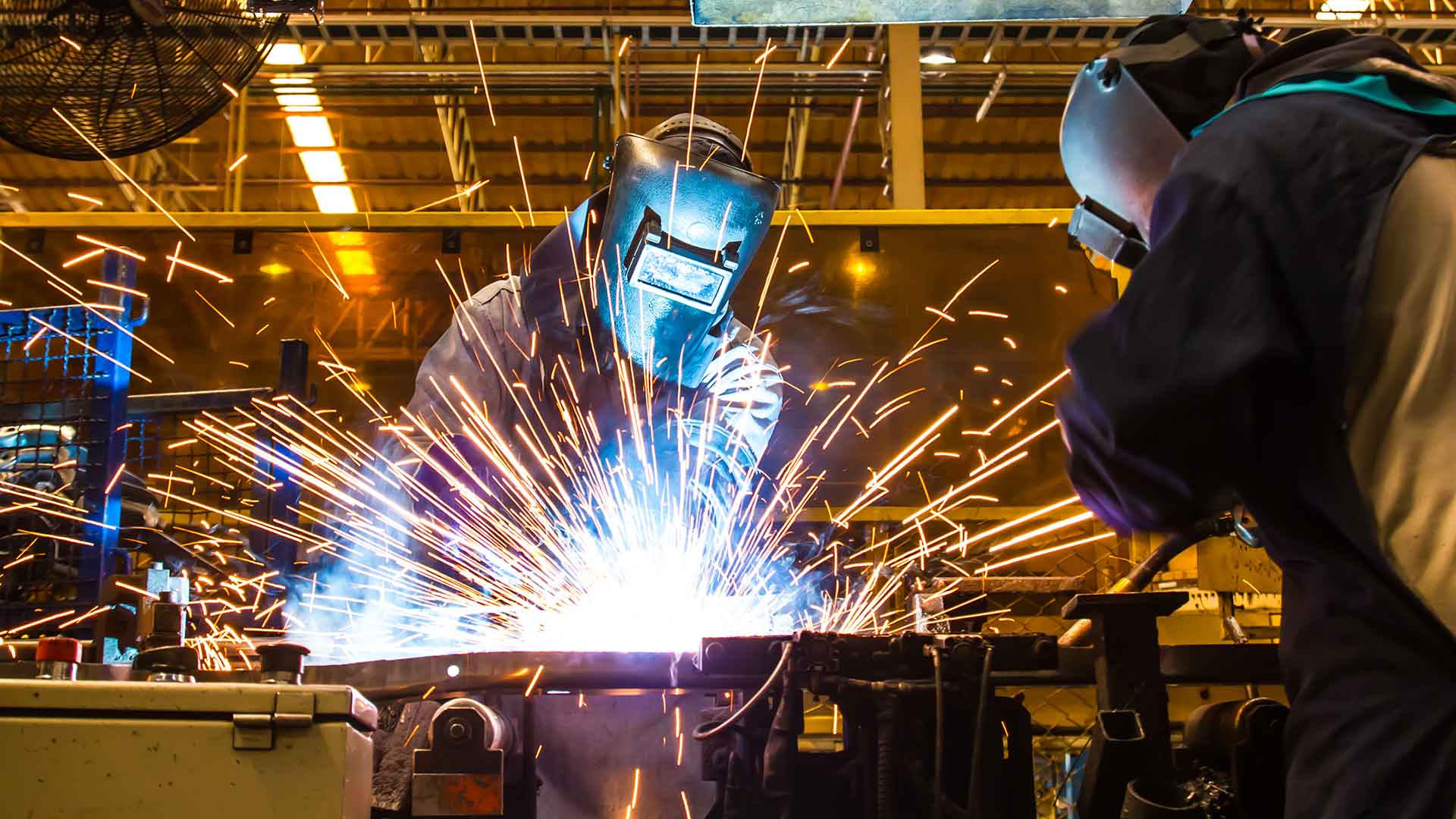 Svetsarbete utförs av två svetsare i en industrilokal. 