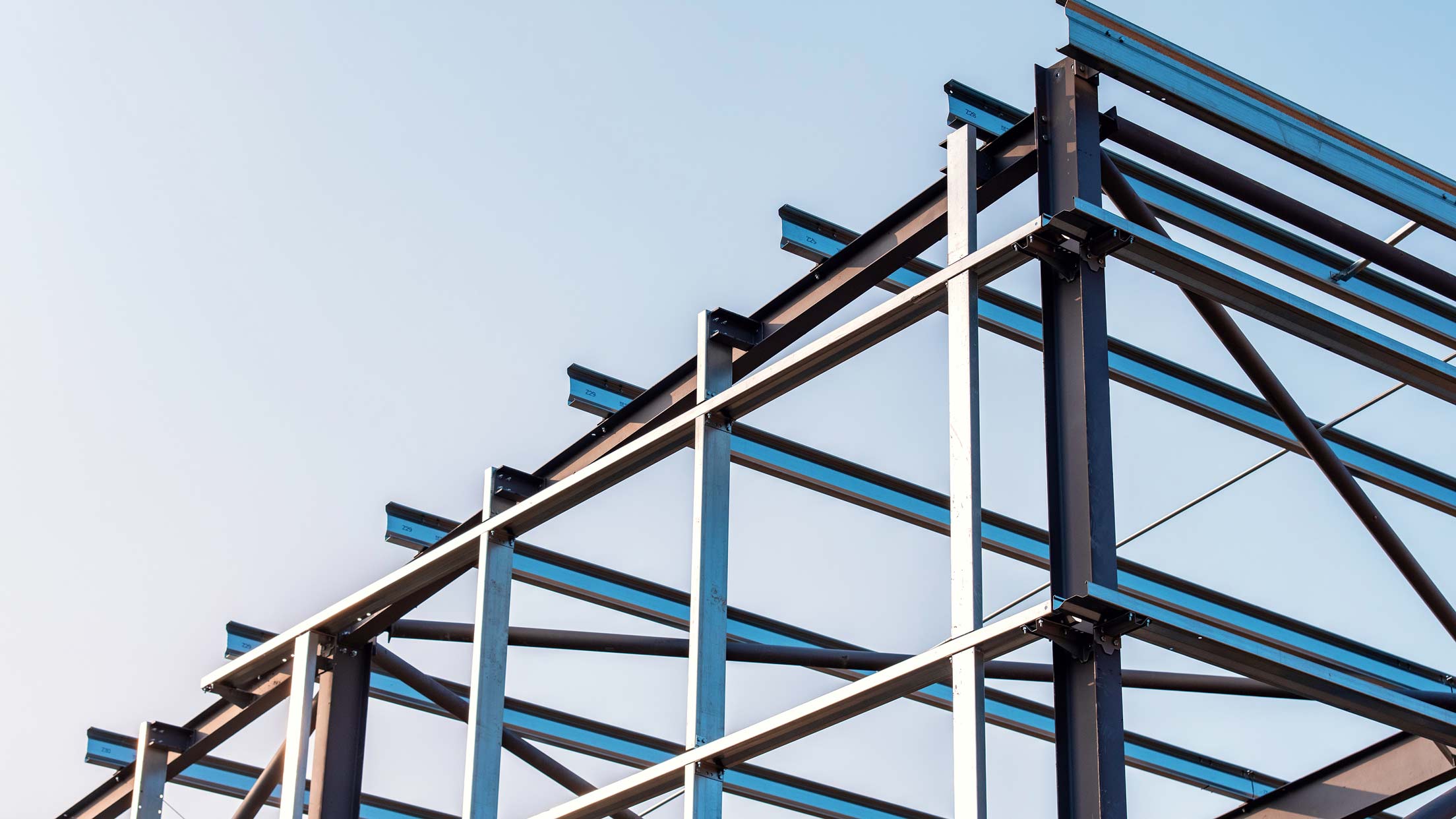 Stålramkonstruktion av en byggnad mot en klarblå himmel.