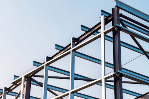 Stålramkonstruktion av en byggnad mot en klarblå himmel.