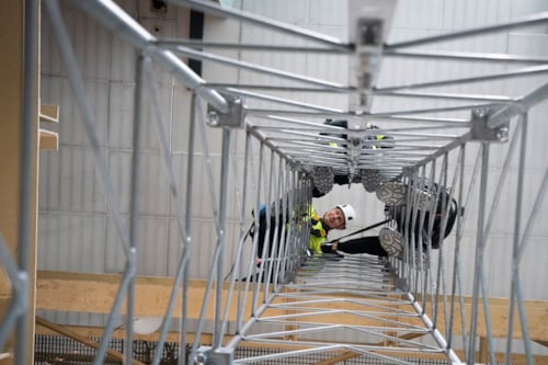 Män med skydds- och fallskyddsutrustninghar klättrat upp i en mast och tittar ner.