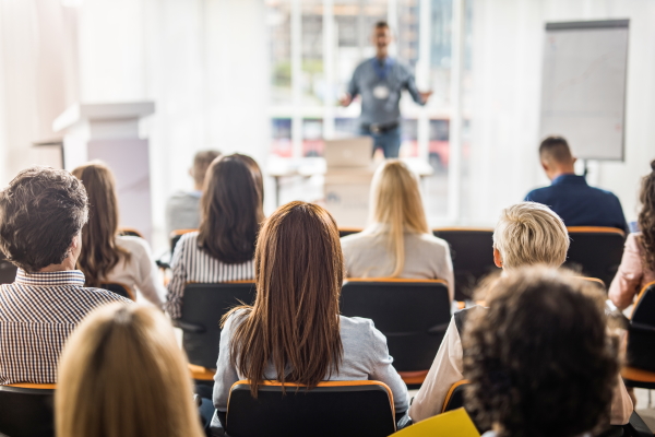 Audience attending a seminar with a Kiwa trainer presenting at the front of a bright conference room